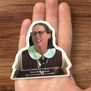 May include: A sticker featuring a woman with a stern expression wearing a brown and white uniform with a white collar. The sticker has the text "You try to keep me trapped in here like a little animal. But I am bustin out, Daddy!"