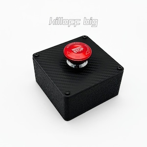 May include: A black box with a carbon fiber texture, topped with a red "EMERGENCY STOP" button. The text "killoff big" is above the box. The button is chrome and the box has four screws.