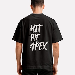 May include: Black t-shirt with the white text "HIT THE APEX" on the back. The text is in a bold, handwritten style. The shirt has short sleeves and a crew neck.