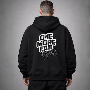 May include: Black hoodie with the text "ONE MORE LAP" in white, along with a graphic of a game controller. The hoodie has a hood and is made of a soft material.