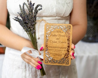 May include: A wooden wedding invitation with a laser-cut design featuring a floral pattern. The invitation reads "Together with our families, Ashley Brooks and Dylan Roberts".