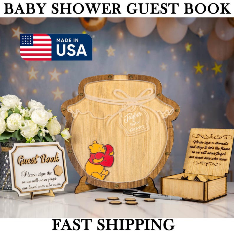 May include: Wooden baby shower guest book with a honey pot design, featuring a Winnie the Pooh graphic. Includes a sign that says "Guest Book" and a box for guest signatures. The text "Baby Shower Guest Book" is at the top.