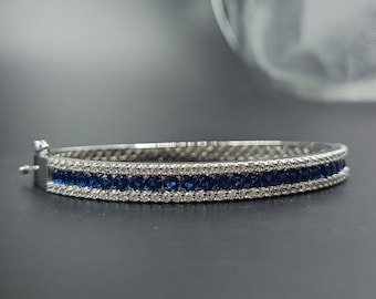 Puede incluir: Un brazalete de plata con una fila de zafiros azules y una fila de diamantes transparentes más pequeños.