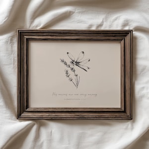 May include: A framed print featuring a black and white illustration of a dragonfly and lavender sprigs. The artwork is set against a beige background, with the text "His mercies are new every morning" and the reference "Lamentations 3:23". The frame is a dark brown.