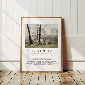 Può includere: Una stampa incorniciata di un dipinto che rappresenta una scena pastorale con pecore che pascolano in un campo. La stampa include il testo "PSALM 23" e il testo del Salmo 23.