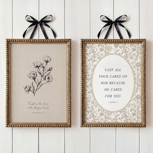 May include: Two framed prints with gold beaded edges and black bows. One features a floral sketch and the text "Trust in the Lord with all your heart." The other has a floral pattern and the text "Cast all your cares on Him because He cares for you."