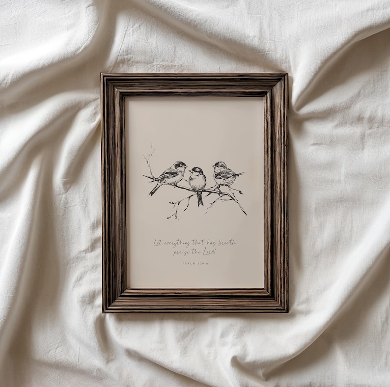 May include: A framed print featuring a drawing of three birds perched on a branch. The artwork is in black and white, set against a beige background. The frame is a dark brown color, and the text "Let everything that has breath praise the Lord!" is written below the birds.