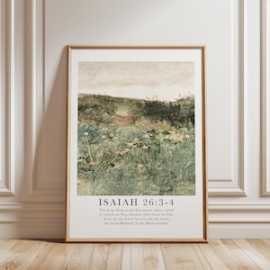 Puede incluir: Una impresión enmarcada que presenta un paisaje pastoral con un campo de flores silvestres y vegetación bajo un cielo nublado. La impresión incluye el texto "ISAIAH 26:3-4" y un versículo bíblico relacionado. El marco es de color marrón claro.