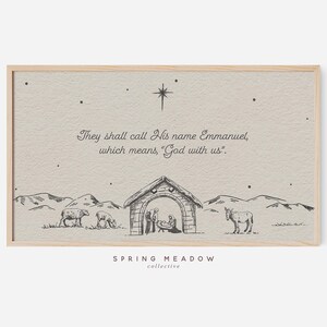 May include: A framed print with a beige background and a black and white illustration of a nativity scene. The text reads, "They shall call His name Emmanuel, which means, 'God with us.'" The print also features a star and the words "SPRING MEADOW collective."