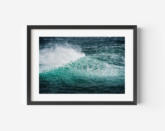 Op de afbeelding: Een grote, krachtige golf breekt in de oceaan. De golf is een levendige turquoise kleur met wit schuim op de top. Het water is diepblauw.