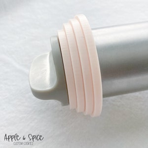 Puede incluir: Primer plano de un rodillo con un anillo de silicona rosa unido al extremo. El anillo está hecho de múltiples capas de silicona.