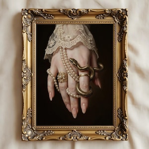 Op de afbeelding: Een ingelijst kunstwerk met een hand versierd met sieraden, waaronder een slangenring en parelkettingen. De hand is geplaatst tegen een donkere achtergrond, omlijst door een sierlijke gouden lijst. Het kunstwerk roept een gevoel van elegantie en mysterie op.