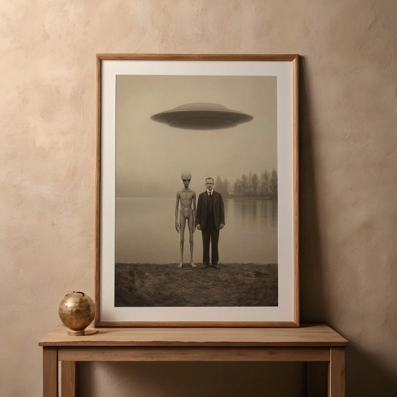 Puede incluir: Impresi&oacute;n enmarcada en tonos sepia que representa a un hombre con traje y un extraterrestre de pie, con un platillo volante encima. La escena est&aacute; ambientada junto a un lago con &aacute;rboles al fondo, creando una atm&oacute;sfera surrealista y misteriosa.
