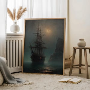 May include: A framed rectangular wall art print featuring a dark, moody maritime scene of a tall ship sailing on calm, misty waters at night. The ship is positioned near a large, jagged rock formation under a faint, glowing moon in the sky.