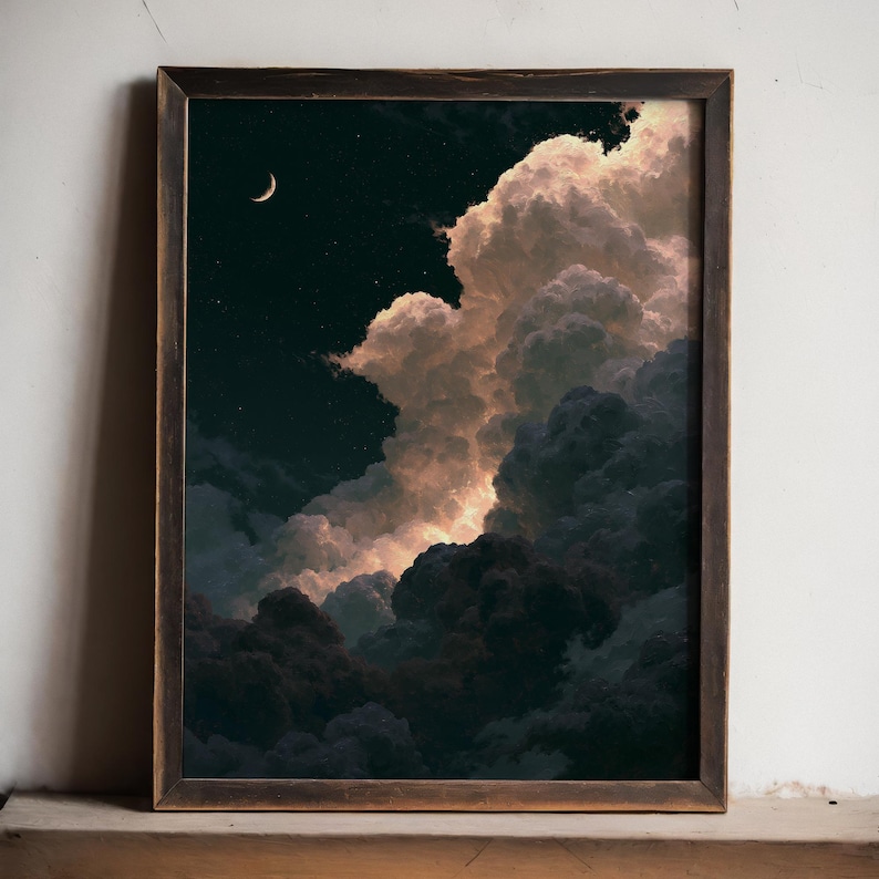 May include: A framed wall art print depicting a night sky with a crescent moon and scattered stars. Large, voluminous clouds dominate the scene, illuminated with warm, golden-toned highlights against deep, dark blue and black shadows.