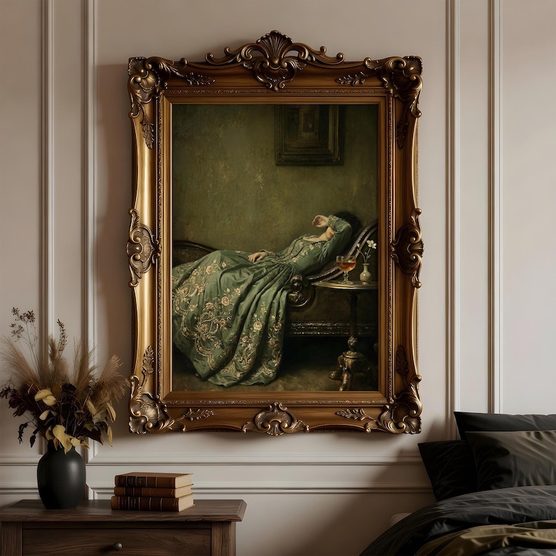May include: A framed oil painting depicting a person in a long, flowing green dress with gold embroidery resting on a dark chaise lounge. Beside them sits a small round table with a glass of amber liquid and a tiny vase with white flowers.