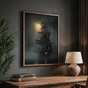 May include: A framed print of a ghostly pirate ship sailing on dark waters under a full moon. The ship is silhouetted against the moon, with tattered sails and glowing lights. The print is in a wooden frame, displayed on a wooden desk.