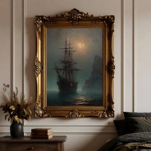 May include: A framed wall art piece featuring a dark, moody painting of a tall ship sailing on misty, dark waters near a rocky cliff under a dim, glowing moon. The artwork is encased in an ornate, antique-style gold frame with intricate carvings.