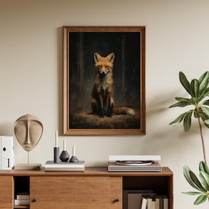 May include: A framed art print featuring a fox. The fox is depicted in a seated position with a reddish-brown coat and a bushy tail. The background shows a dark forest scene. The frame is made of wood.