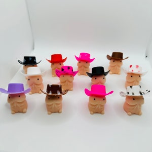 Op de afbeelding: Een verzameling van 12 kleine, roze, witte en bruine figuurtjes die cowboyhoeden dragen. De figuurtjes dragen allemaal hoeden in verschillende kleuren met verschillende patronen.