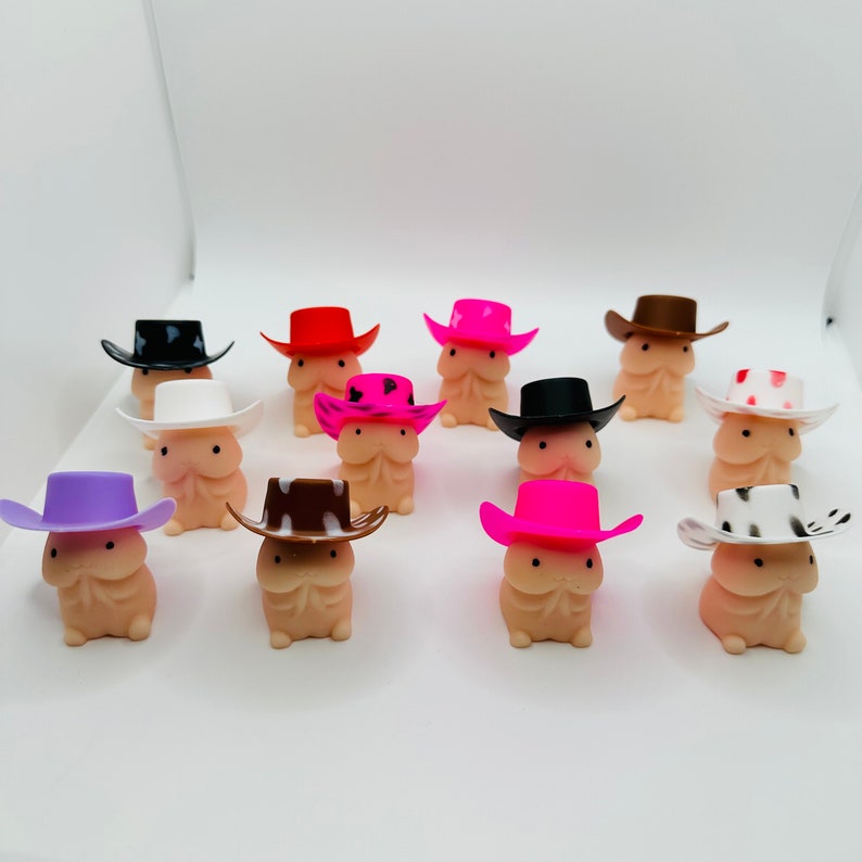 Op de afbeelding: Een verzameling van 12 kleine, roze, witte en bruine figuurtjes die cowboyhoeden dragen. De figuurtjes dragen allemaal hoeden in verschillende kleuren met verschillende patronen.