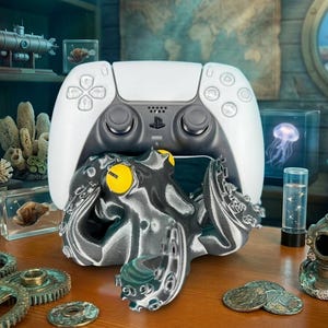 May include: A white and black video game controller with a detailed, gray octopus-shaped stand. The octopus has yellow eyes. The scene includes nautical-themed decor, such as gears, a diving helmet, and a submarine model.