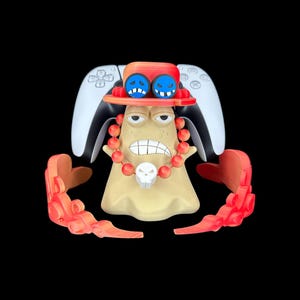 May include: A unique, tan-colored figurine with a red hat and necklace, featuring a skull pendant. The figurine has a white PlayStation controller on the back and red flame-like accents. The hat has two blue, cartoon-like faces.