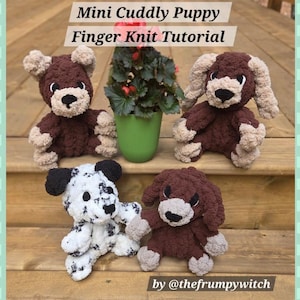 May include: Four handmade plush toys featuring a Mini Cuddly Puppy Finger Knit Tutorial. Three puppies are brown with tan accents, and one is white with black spots. Each has dark eyes and a nose. A green potted plant sits in the center.