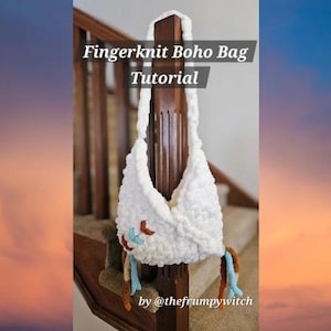 Puede incluir: Un bolso boho blanco tejido con los dedos con una apariencia texturizada, colgado de un poste de madera. El bolso presenta detalles decorativos en marrón, azul y naranja. El texto "Fingerknit Boho Bag Tutorial" se muestra en la parte superior.