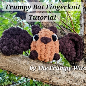 Puede incluir: Tutorial de tejido de dedos de murciélago de felpa hecho a mano. El murciélago es marrón y canela con alas moradas oscuras, posado en una rama de árbol. Se muestra el texto "Frumpy Bat Fingerknit Tutorial by The Frumpy Witch".