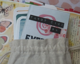 May include: A white canvas bag with a pink and white tarot zine inside. The zine has a black label that says "Tarot Zine 04".