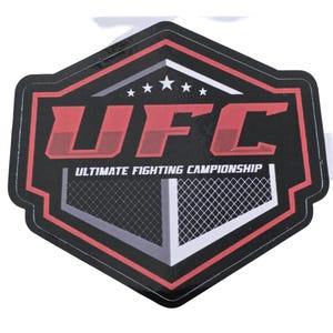 Puede incluir: Una pegatina hexagonal negra y roja con el logotipo de UFC y el texto "ULTIMATE FIGHTING CHAMPIONSHIP".