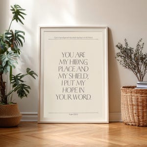 May include: Framed art print with the text "YOU ARE MY HIDNG PLACE AND MY SHIELD; I PUT MY HOPE IN YOUR WORD." The print is in a white frame and features a beige background with black text. Psalm 119:114 is at the bottom.