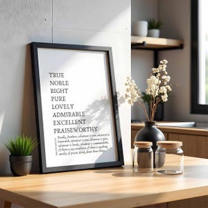 Pode incluir: Uma impressão emoldurada em preto com fundo branco e texto preto. O texto diz "Verdadeiro, Nobre, Certo, Puro, Agradável, Admiravel, Excelente, Louvável". Abaixo do texto há uma citação de Filipenses 4:8. A impressão está sobre uma mesa de madeira com uma pequena planta em vaso e dois frascos de vidro com tampas de madeira.