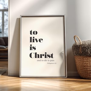 Può includere: Stampa artistica incorniciata con le parole "to live is Christ and to die is gain" in nero. La stampa ha uno sfondo color crema ed è in una cornice argentata. Un cesto intrecciato con la parte superiore grigia e soffice è sullo sfondo.
