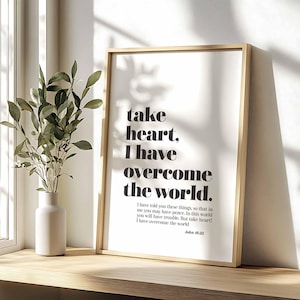 Può includere: Una stampa incorniciata con sfondo bianco e testo nero che recita "take heart, I have overcome the world." Il testo è in grassetto, senza grazie. Sotto il testo c'è una citazione da Giovanni 16:33, che recita "Vi ho detto queste cose perché abbiate pace in me. Nel mondo avrete tribolazione, ma abbiate coraggio, io ho vinto il mondo." La citazione è in un carattere più piccolo, con grazie.