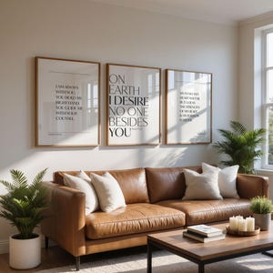 May include: Three framed art prints with inspirational quotes hang above a brown leather sofa. The prints have a white background with black text. A wooden coffee table and potted plants complete the living room decor.