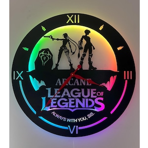 May include: Black circular wall clock with the text "Arcane League of Legends" and the phrase "Always with you, sis." The clock features a silhouette of two characters and a colourful LED light display. The clock hands are red.