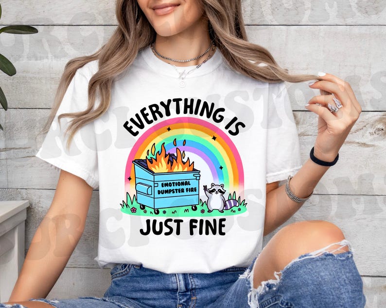 K&ouml;nnte beinhalten: Wei&szlig;es T-Shirt mit einem Regenbogen, einem M&uuml;lltonnenfeuer und einem Waschb&auml;ren. Der Text auf dem Shirt lautet "Alles ist gut."