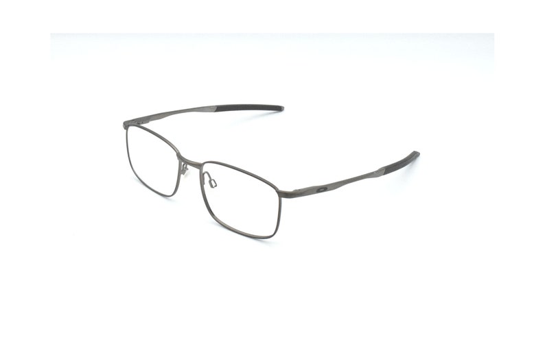 May include: A pair of silver-toned metal spectacles with a rectangular frame and black earpieces.