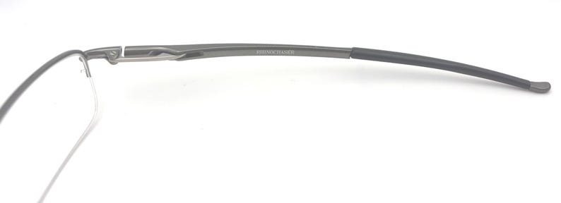 May include: A pair of rimless eyeglasses with a dark gray metal frame. The temples curve gently, and the text "BOTTEGA VENETA" is visible on the temple. The glasses are set against a white background.