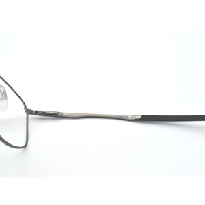 May include: A pair of silver-toned spectacles with black temple tips. The brand name "SAFFIANO" is printed on the temple.