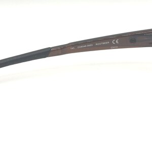 May include: Brown rectangular eyeglasses with black temples. The glasses have a sleek, modern design. The temple arm has the text "CE" and other markings. The glasses are designed for vision correction.