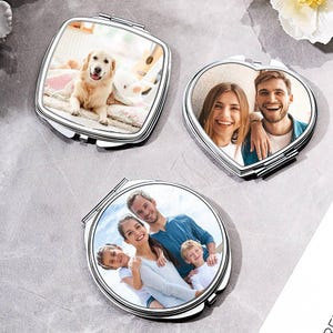 Può includere: Tre specchietti compatti argentati di diverse forme: quadrato, a cuore e rotondo. Ogni specchietto contiene una fotografia. Lo specchietto quadrato mostra un golden retriever. Lo specchietto a cuore mostra una coppia. Lo specchietto rotondo mostra una famiglia.