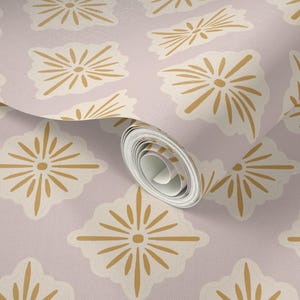 May include: A roll of wallpaper featuring a repeating pattern of stylized, starburst-like shapes in cream and gold against a pale lavender background. The design has a retro, mid-century modern aesthetic.