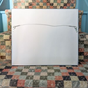 The back of a framed work of art on a stair with checkered vintage runner.