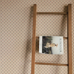 May include: A wooden ladder leaning against a wall with a magazine titled "Kinfolk" on the middle rung. The magazine features a person wearing a white dress and a wide-brimmed hat standing in a field.