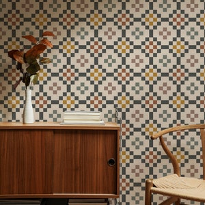 May include: A mid-century modern cabinet with sliding doors and shelves, filled with books. The cabinet is in front of a wall with a geometric pattern wallpaper in shades of beige, brown, gray, and yellow.
