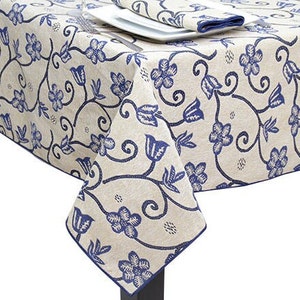 May include: A beige tablecloth with a blue floral pattern. The tablecloth is square shaped and made from woven fabric.