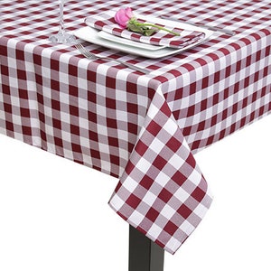May include: A red and white gingham tablecloth with a white plate and a pink flower on top.